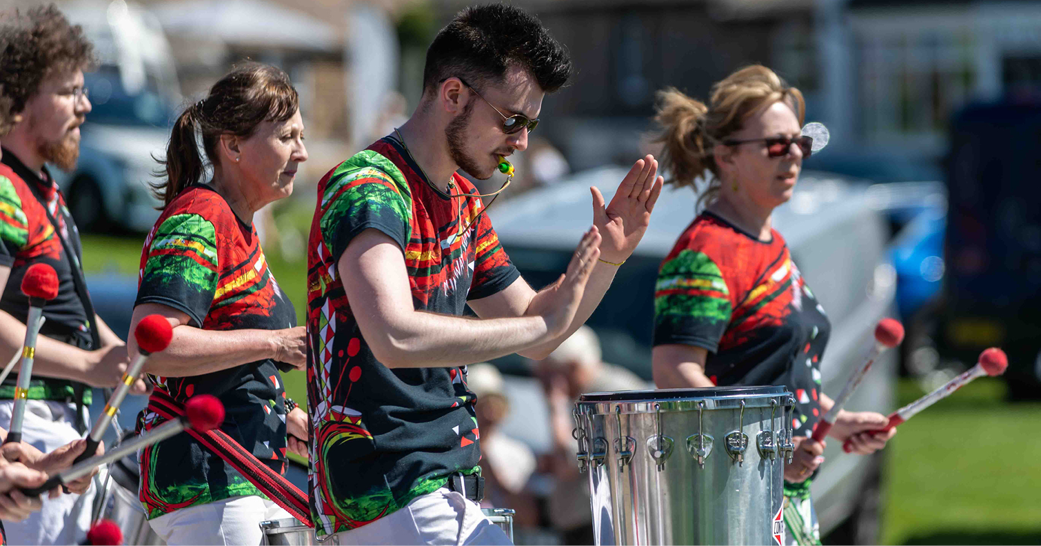 mixture of men and women playing the drums as part of a band